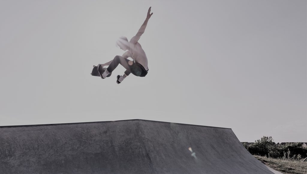 A skateboarder is flying in the air with one arm raised