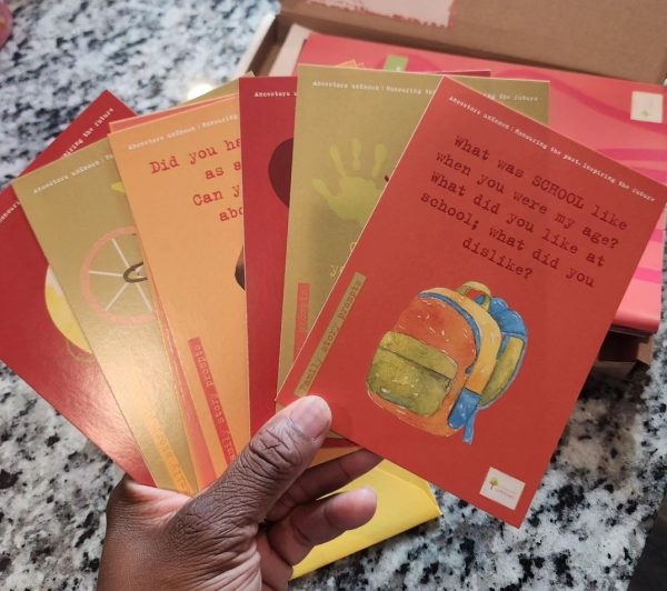 A hand holds colourful family storytelling cards from the Family History Toolkit