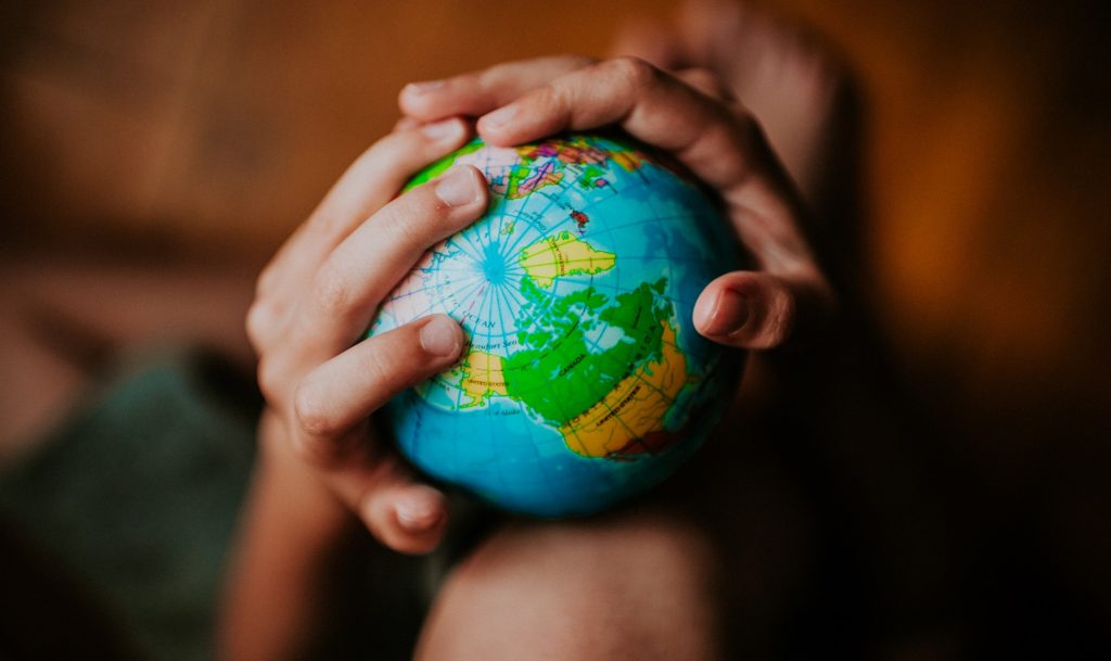A child's hands holding a small, colorful globe