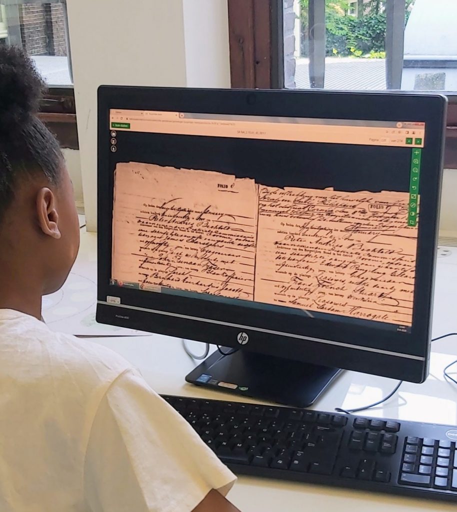 A young person looks at a computer that shows an archived document - enhance uk history education