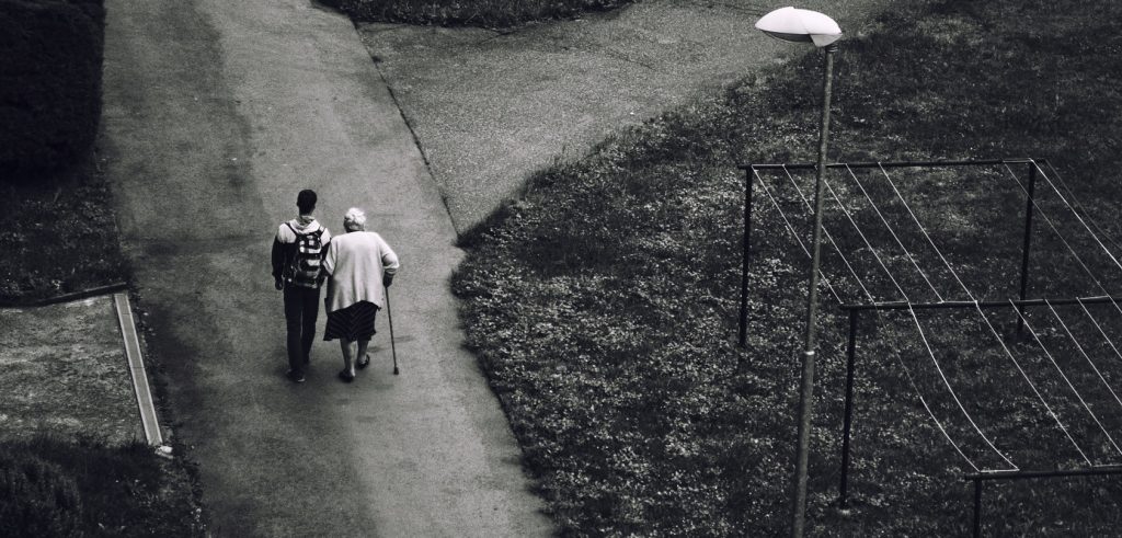 a black and white image taken from above with an older woman walking with a younger man